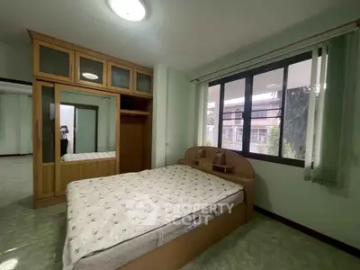 Spacious bedroom with large window and built-in wardrobe in modern apartment.