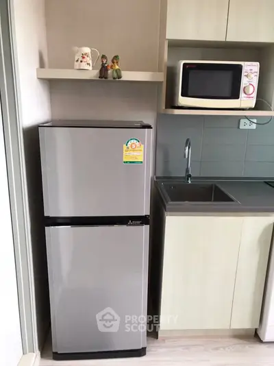 Modern kitchen with sleek fridge and microwave in compact layout
