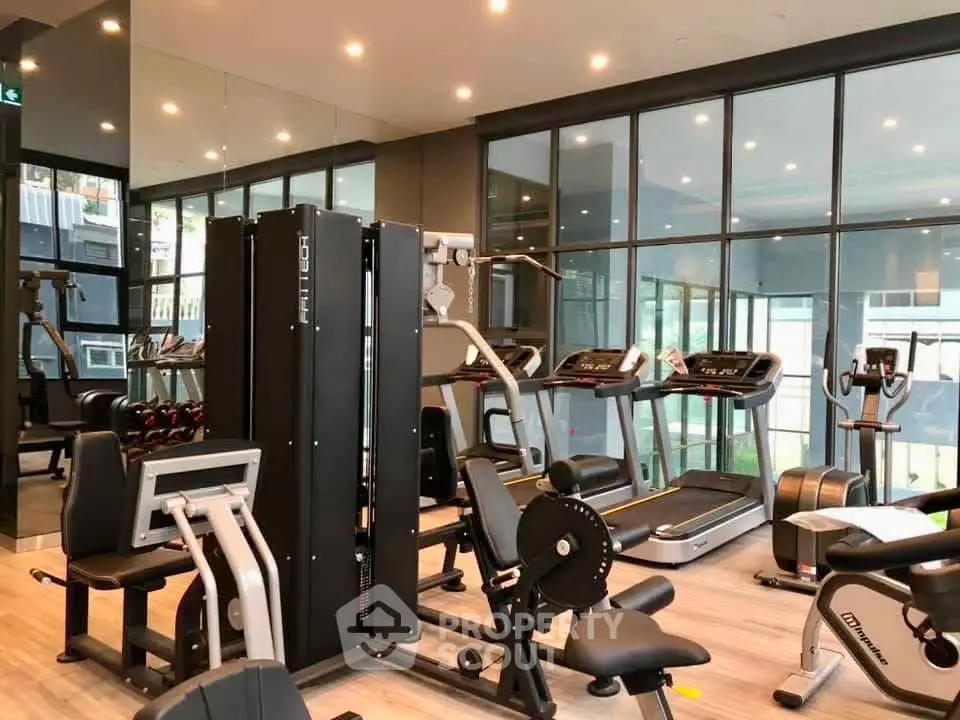 Modern gym with state-of-the-art equipment and large windows in a luxury residential building.