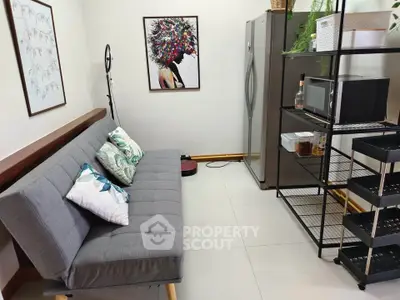 Modern living area with stylish sofa, artwork, and sleek kitchen appliances.
