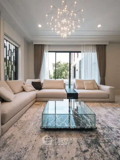Luxurious living room with elegant chandelier and modern glass coffee table.