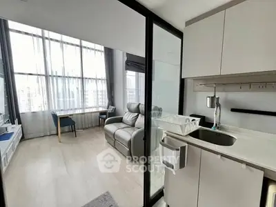 Modern apartment with sleek kitchen and cozy living area featuring large windows.
