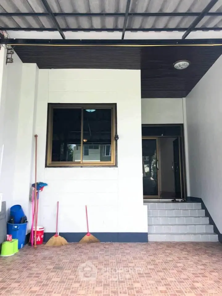 Charming home entrance with tiled steps and practical cleaning tools, perfect for a welcoming and organized space.