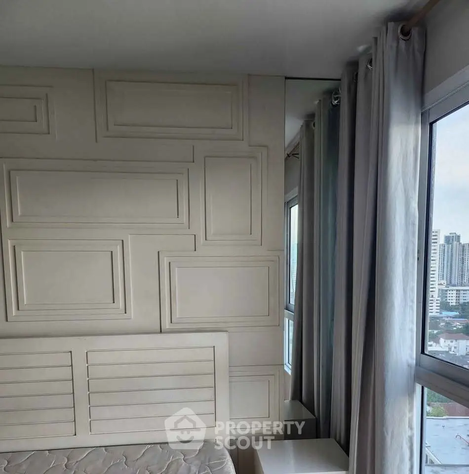 Modern bedroom with stylish wall paneling and city view from large windows.