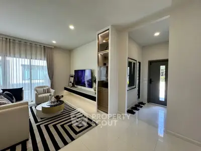 Modern living room with sleek design and large TV, featuring stylish furniture and elegant decor.