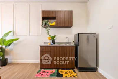 Modern compact kitchen with wooden cabinets and stainless steel fridge