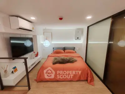 Modern bedroom with orange bedding, sleek TV setup, and ambient lighting