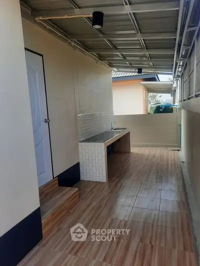 Modern outdoor kitchen with tiled flooring and sleek countertop in a covered patio area.