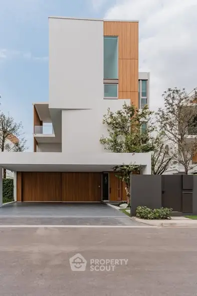 Modern architectural home with sleek design and wooden accents, featuring a spacious driveway.