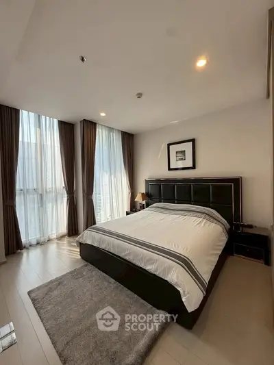 Spacious bedroom with modern decor and large windows offering natural light.
