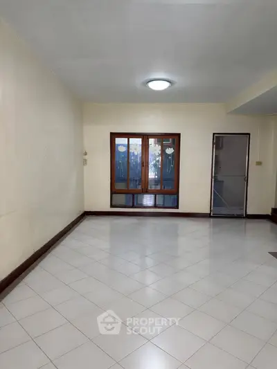 Spacious empty room with tiled floor and large window, perfect for customization.