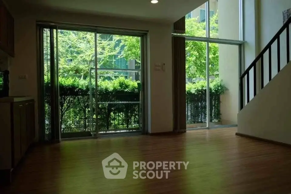 Spacious living room with large windows and garden view, perfect for natural light lovers.
