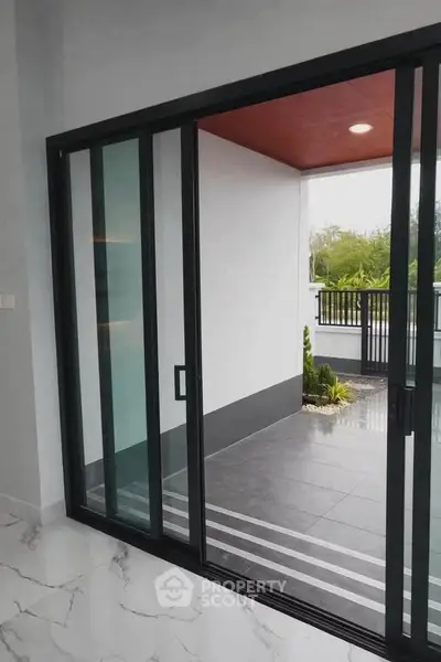 Modern home with sliding glass doors opening to a stylish balcony with sleek flooring and greenery.