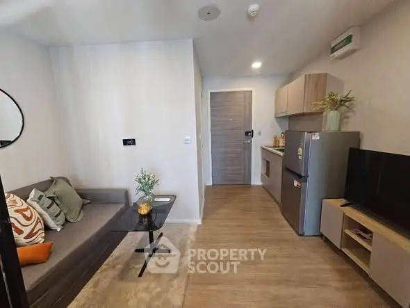 Modern compact living room with kitchenette, featuring stylish decor and cozy ambiance.