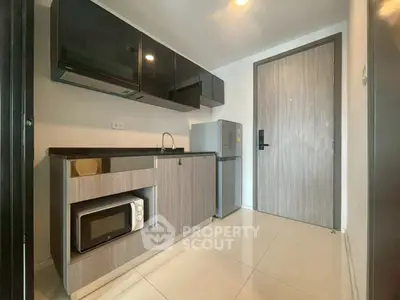 Modern compact kitchen with sleek cabinets, microwave, and mini fridge in a stylish apartment.