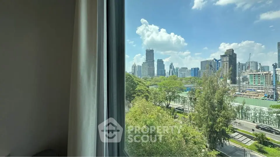 Stunning cityscape view from a high-rise window, showcasing lush greenery and modern skyscrapers under a clear blue sky.