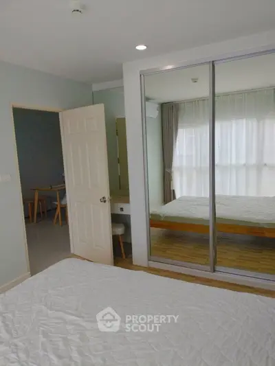Spacious bedroom with mirrored closet doors and natural light
