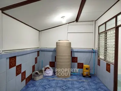 Utility room with water tank and tiled walls, featuring practical storage solutions.