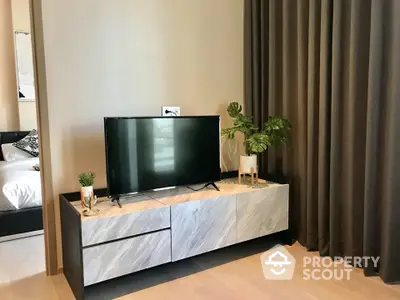 Modern living space with sleek TV console and warm wooden flooring, complemented by elegant drapery and tasteful greenery.