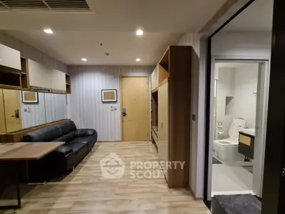 Modern apartment interior with open living area and visible bathroom, featuring sleek design and wooden flooring.