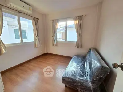 Bright room with large windows and a wrapped sofa, showcasing potential for cozy living space.