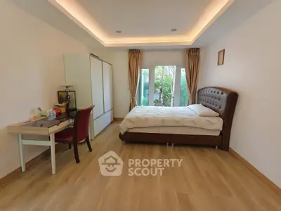 Spacious bedroom with modern decor and garden view through glass doors.