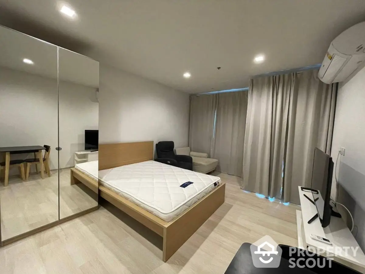 Modern bedroom with minimalist design, featuring a large mirror wardrobe and cozy seating area.