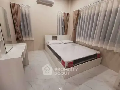 Modern bedroom with sleek white furniture and large windows with curtains, creating a bright and inviting space.