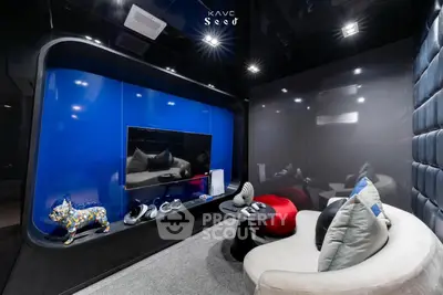Modern entertainment room with sleek design and vibrant blue accent wall, featuring a cozy seating area and stylish decor.