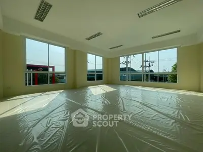 Spacious sunlit room with large windows and modern lighting, ideal for versatile use.