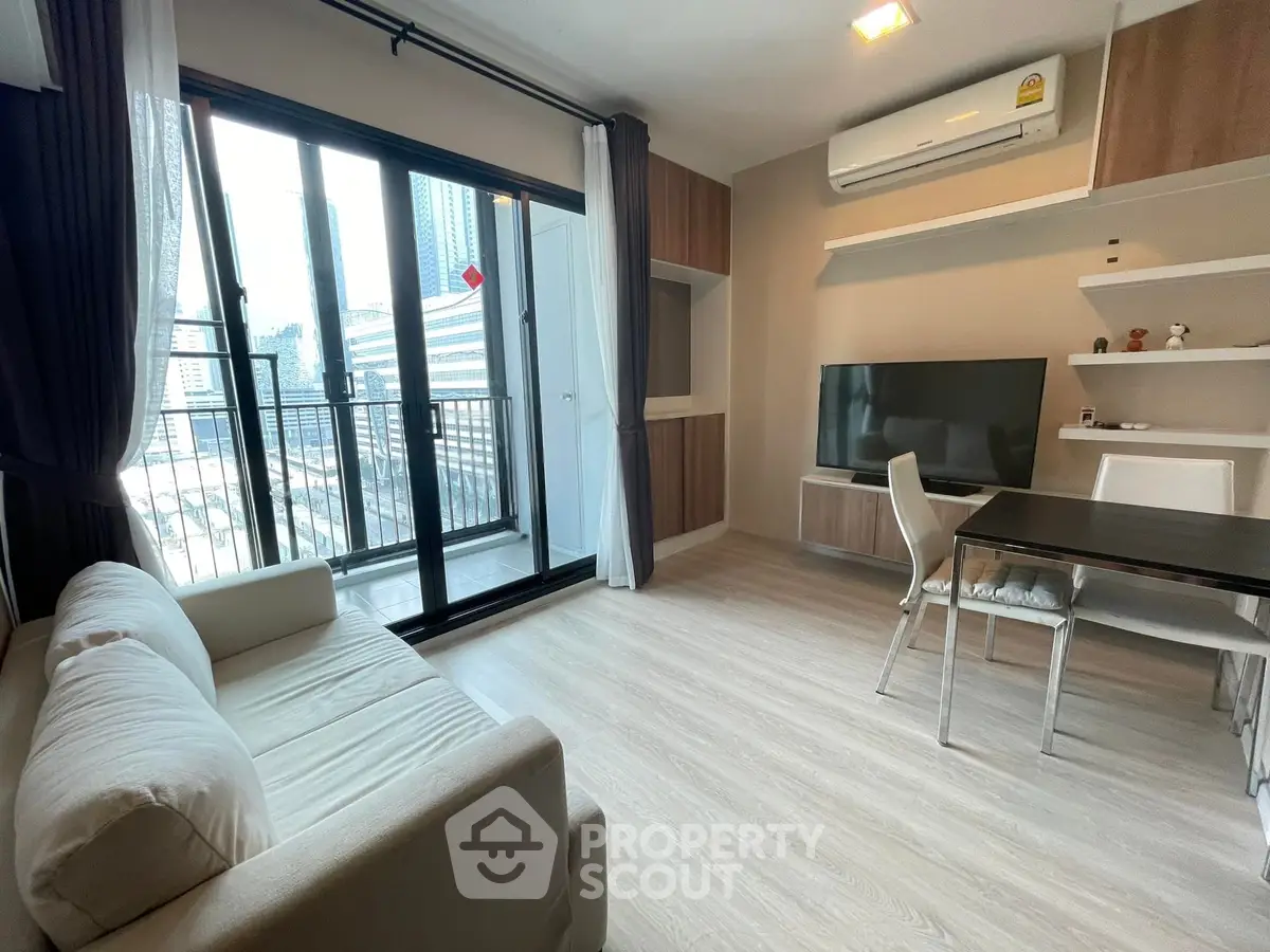 Modern living room with balcony view, featuring sleek furniture and air conditioning.