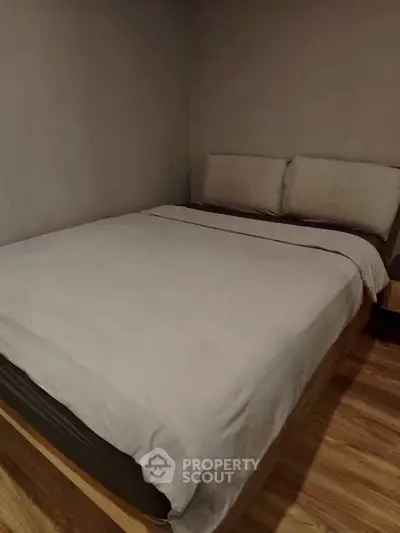 Cozy bedroom with wooden flooring and comfortable bedding, perfect for relaxation.