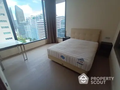 Spacious bedroom with large windows offering a panoramic city view, ample natural light, and modern flooring in a high-rise apartment.