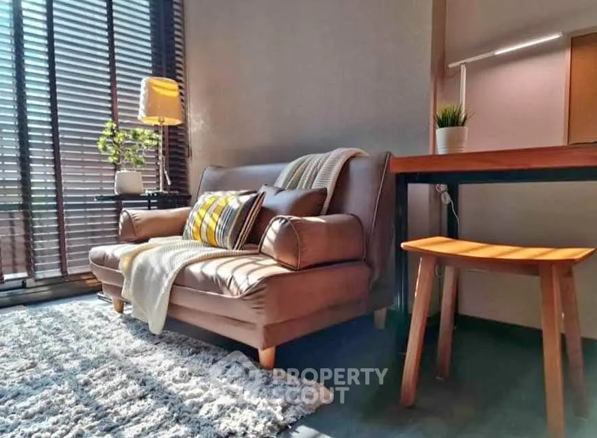 Cozy living room with stylish sofa, modern decor, and natural light through large windows.