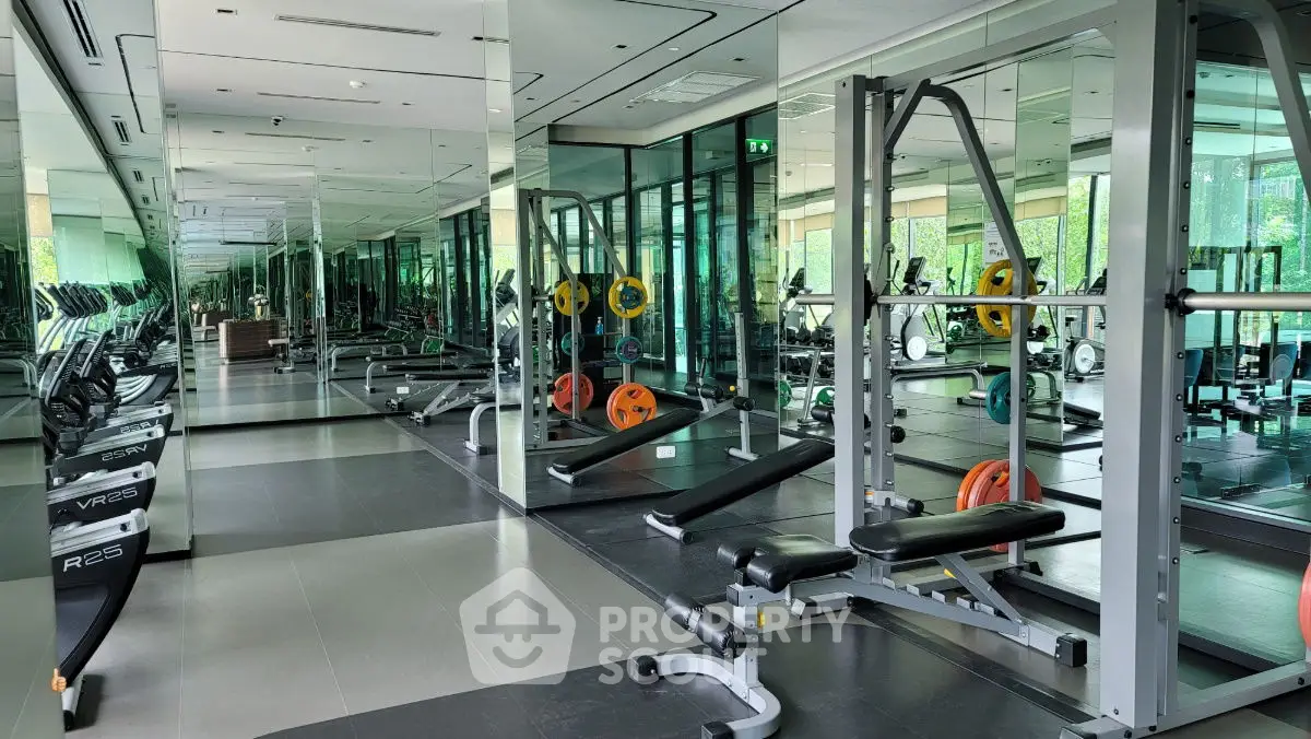 Spacious modern gym with mirrored walls and state-of-the-art equipment in luxury building.