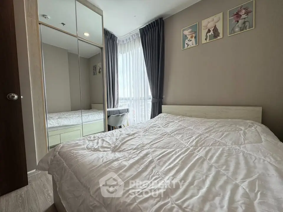 Cozy bedroom with large window and mirrored wardrobe in modern apartment