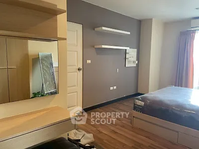 Modern bedroom with wooden flooring and stylish furniture, featuring a cozy bed and decorative shelves.
