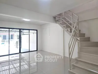 Spacious modern living room with sleek staircase and large glass doors