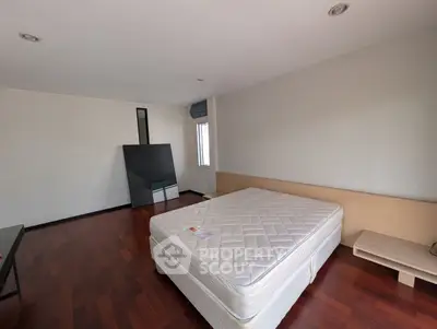 Spacious bedroom with hardwood floors and large window for natural light.