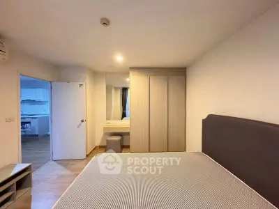 Spacious bedroom with modern furnishings and a view into the kitchen area, perfect for comfortable living.