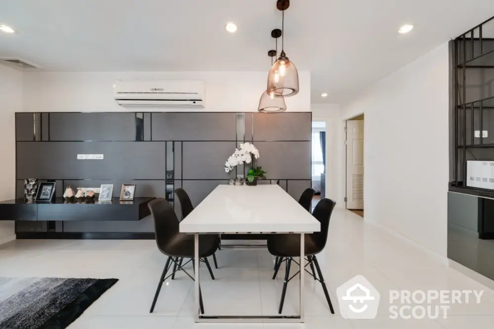 Modern dining area with sleek black furniture and elegant lighting in a contemporary home.