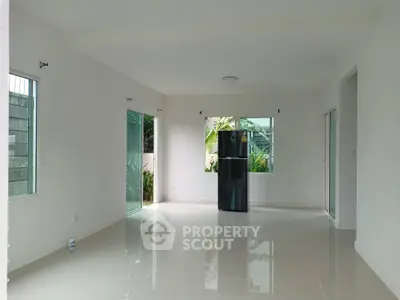 Spacious open-plan living area with glossy floors and large windows, featuring a modern refrigerator.