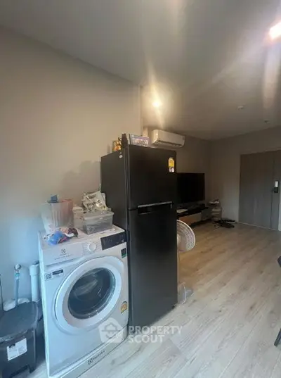 Modern apartment interior with washing machine and fridge in open layout living space.