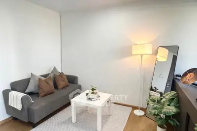 Cozy living room with modern decor, featuring a gray sofa, white coffee table, and stylish floor lamp.