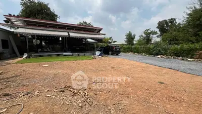 Spacious outdoor area with gravel driveway and covered patio, ideal for versatile use.