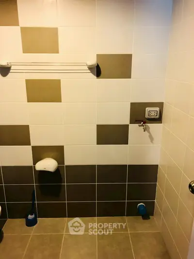 Modern bathroom with tiled walls and floor, featuring a towel rack and plumbing fixtures.