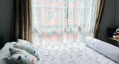 Cozy bedroom with large window and elegant curtains, offering a bright and inviting atmosphere.