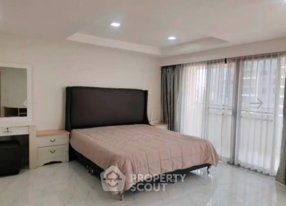 Spacious bedroom with large windows and modern decor in a luxury apartment.