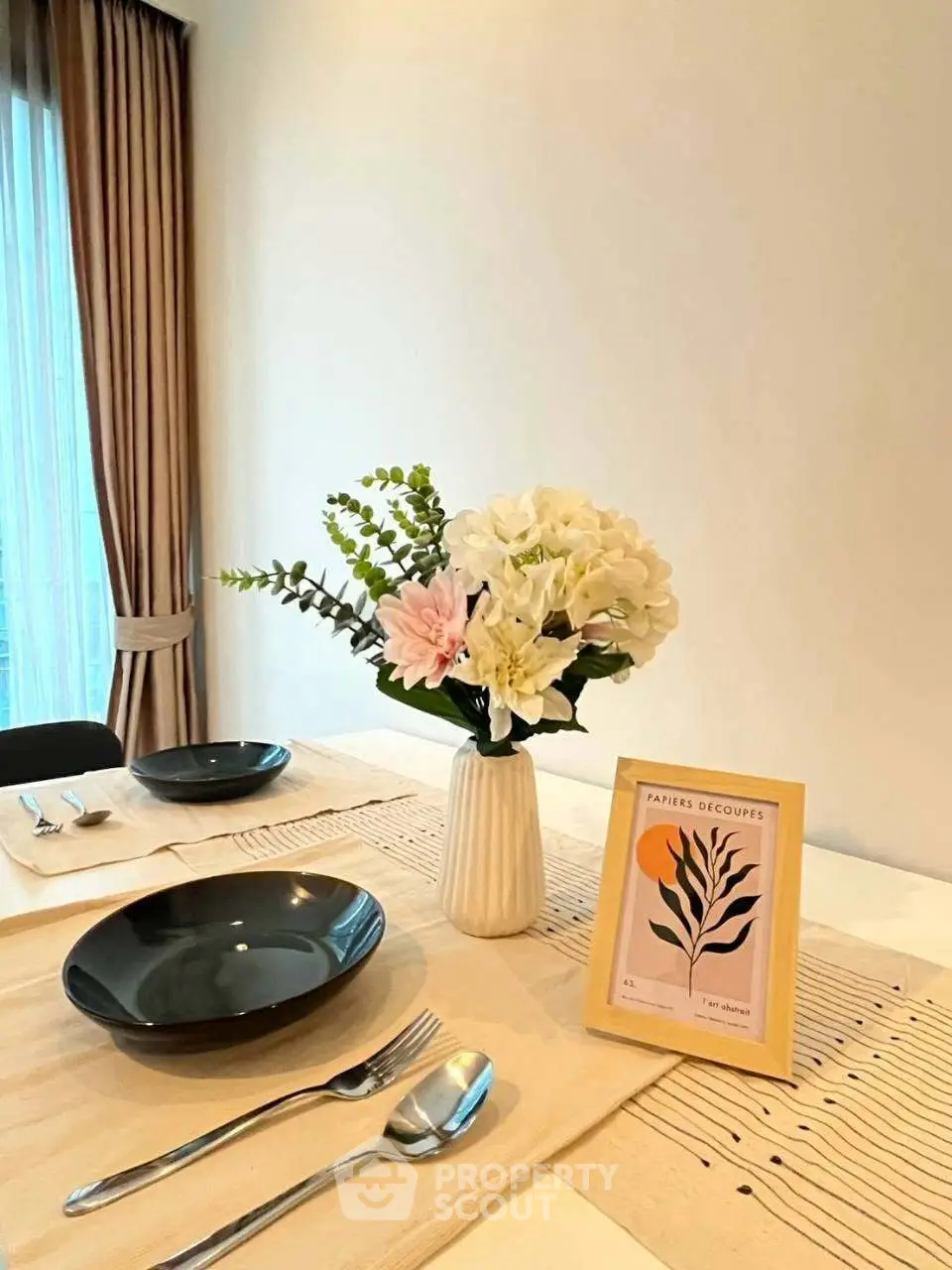 Elegant dining setup with floral centerpiece and modern tableware in a cozy apartment.