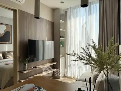 Modern living room with large TV, natural light, and stylish decor in a cozy apartment.